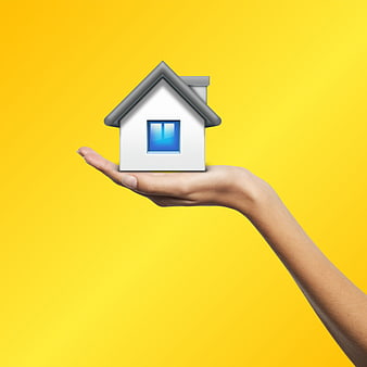 Hand holding miniature house model on yellow background