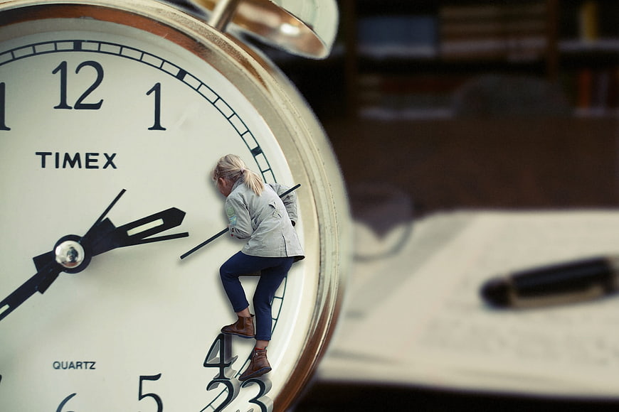 Tiny woman climbing giant alarm clock face