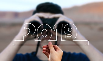 Man with binoculars holding 2019 outline in desert