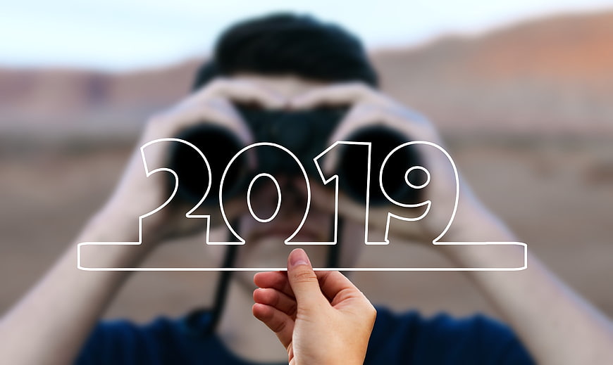 Man with binoculars holding 2019 outline in desert