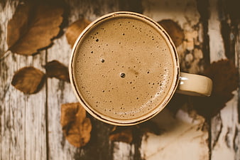 Top View of Frothy Coffee Cup with Autumn Leaves