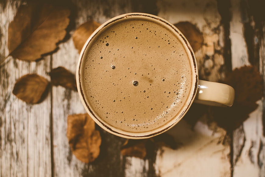 Top View of Frothy Coffee Cup with Autumn Leaves