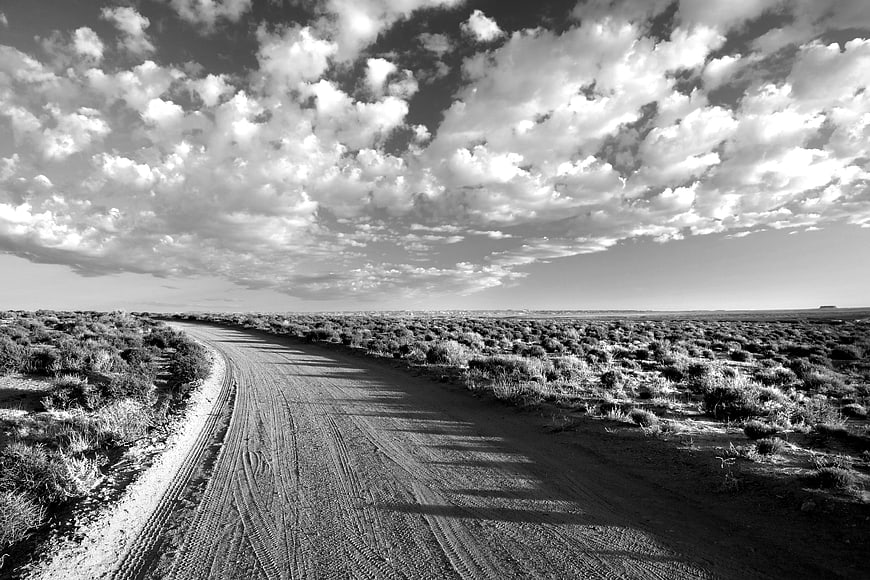 Black and White Desert Road Under Dramatic Clouds