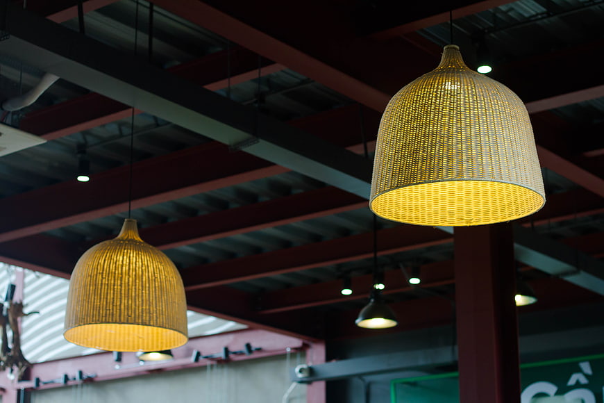 Woven rattan pendant lights hanging from industrial ceiling