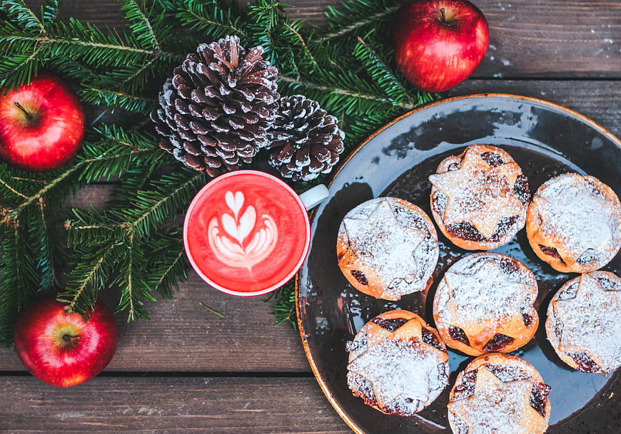 Christmas cookies, red latte, apples, and pine branches on wood