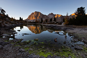 Alpine lake reflecting golden sunset on rugged mountain peaks
