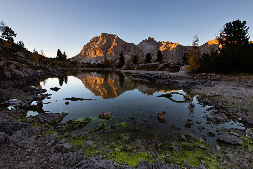 Alpine lake reflecting golden sunset on rugged mountain peaks