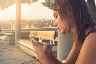 Young Woman Texting on Smartphone at Sunset