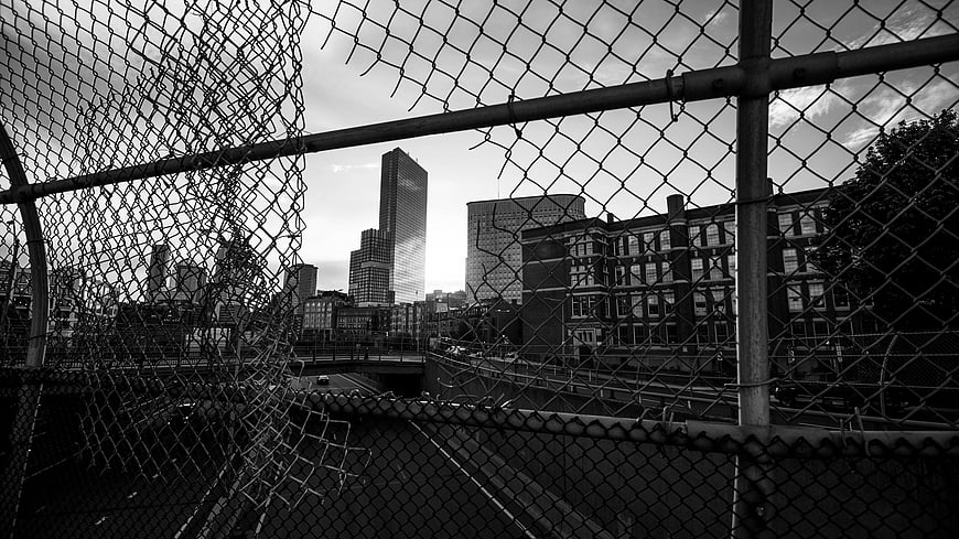 Black and white city skyline view through chain link fence