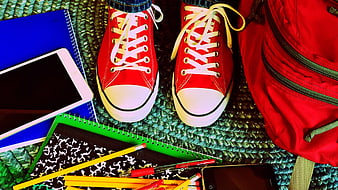Red sneakers and school supplies on woven mat
