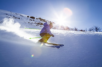 Skier carving down snowy mountain slope in bright sunlight