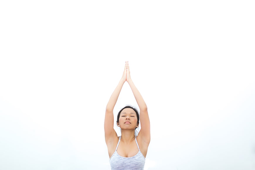 Woman meditating with hands raised in prayer position