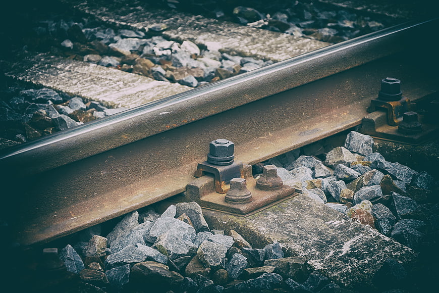 Close-up of rusty railway track with gravel and concrete sleepers