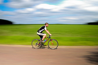 Man Cycling Fast on Country Road with Motion Blur