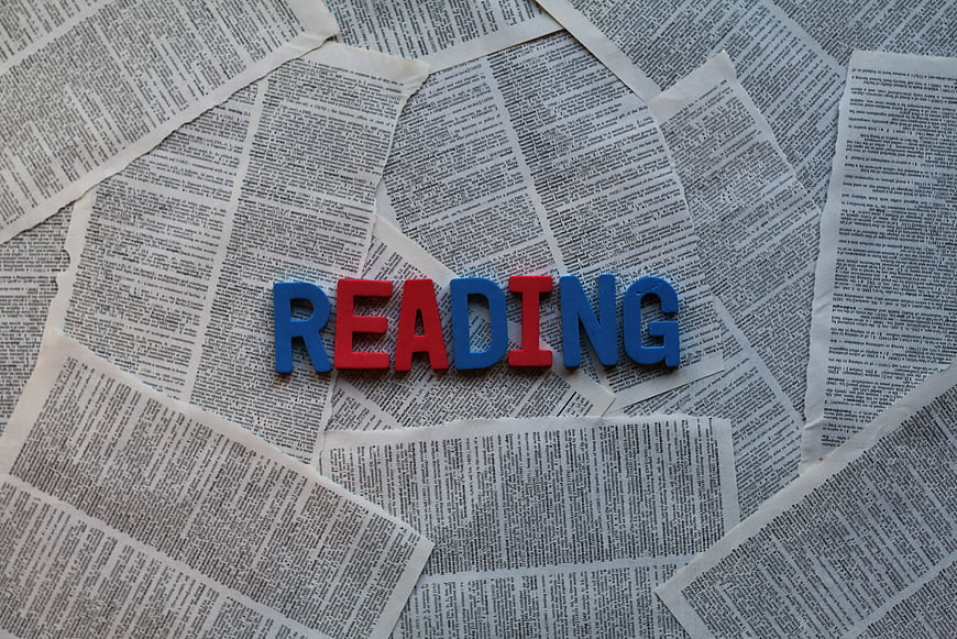 Reading spelled with colorful letters on newspaper background