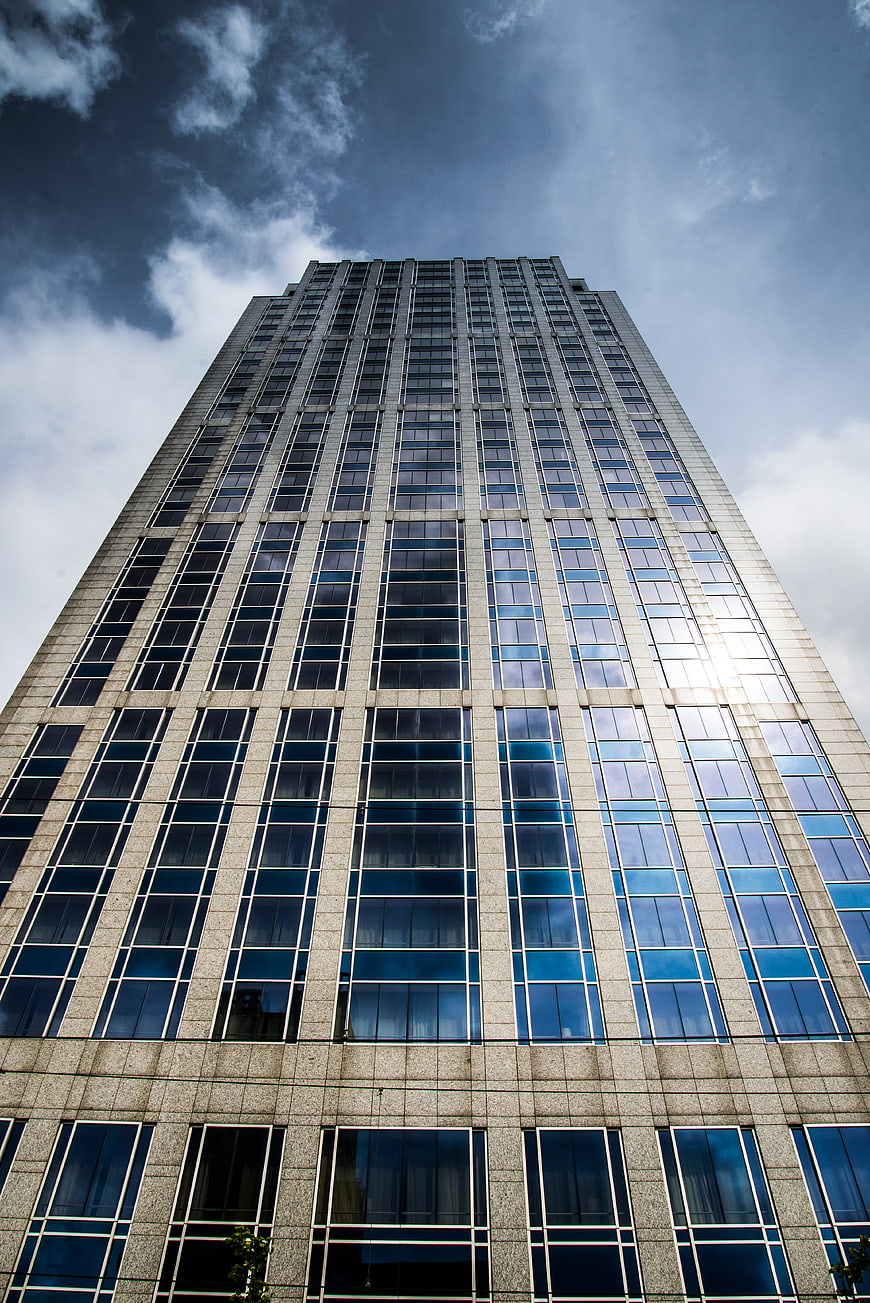 Low angle view of modern glass skyscraper against blue sky