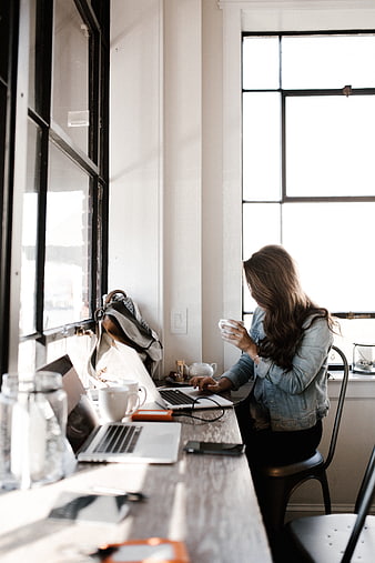 Woman working on laptop in bright office with coffee