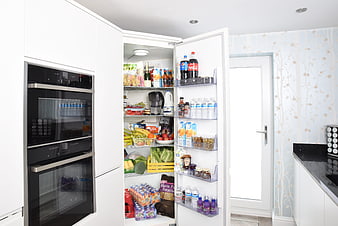 Open Refrigerator Filled With Fresh Food In Modern White Kitchen