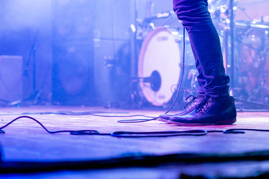 Musician's Boots on Stage with Drum Kit Background