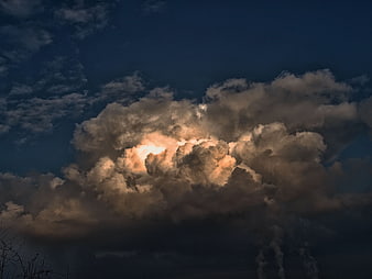 Dramatic storm clouds with sun breaking through dark sky