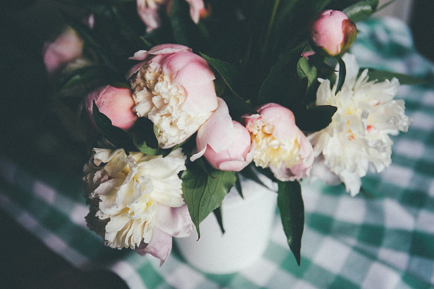 Pink and white peonies in a vase on a checkered tablecloth