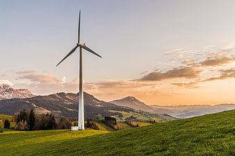 Wind Turbine on Green Hill at Sunset with Mountains