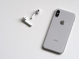 Silver iPhone and White Wireless Earbuds on White Background