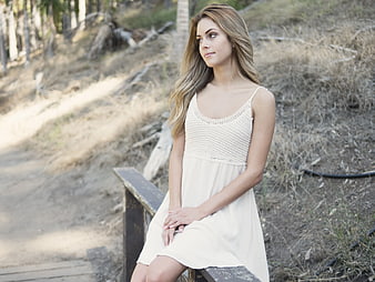 Woman in White Dress Sitting on Wooden Bench Outdoors