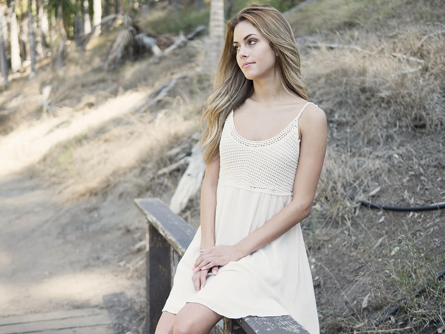 Woman in White Dress Sitting on Wooden Bench Outdoors