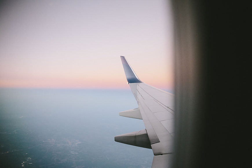 Airplane Wing View at Sunset Over Clouds