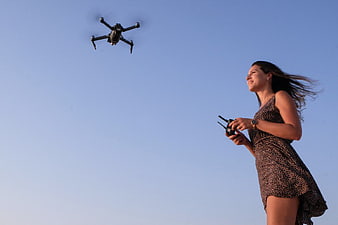 Woman Flying Drone Against Blue Sky