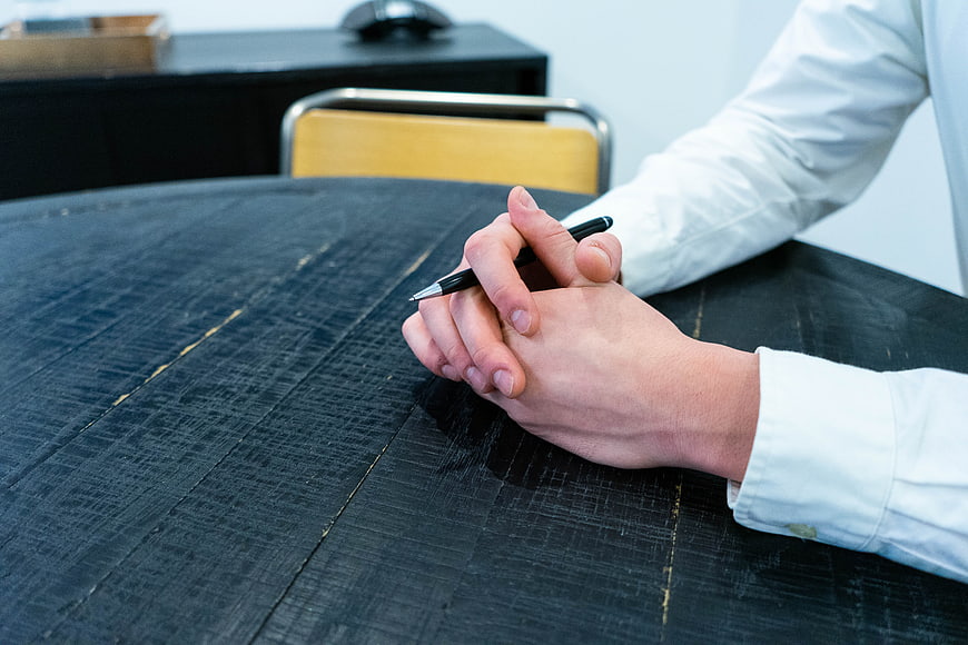 Close-up of hands holding a pen on a dark wooden table