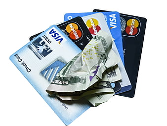 Stack of credit cards and crumpled cash on white background