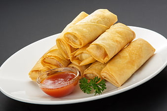 Golden fried spring rolls with sweet chili sauce on a white plate