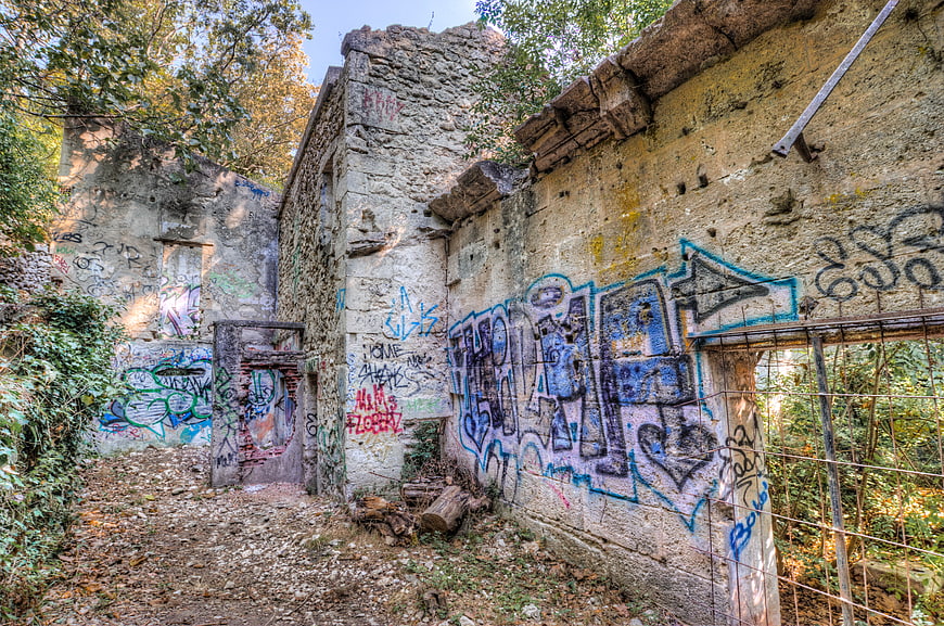 Abandoned stone ruins with colorful graffiti in overgrown forest