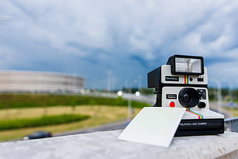 Vintage Polaroid Camera on Balcony with Blurred City Background