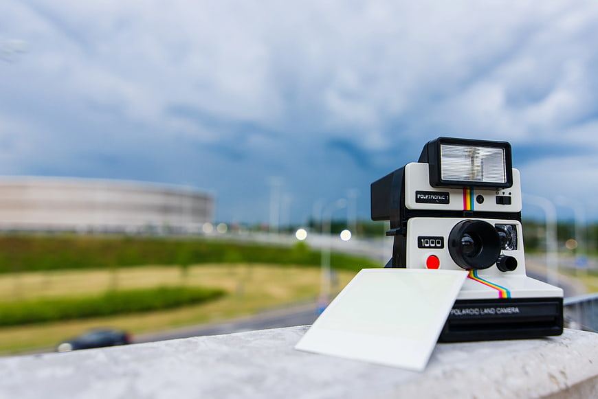 Vintage Polaroid Camera on Balcony with Blurred City Background