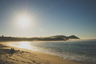 Couple Sitting on Sandy Beach at Golden Hour