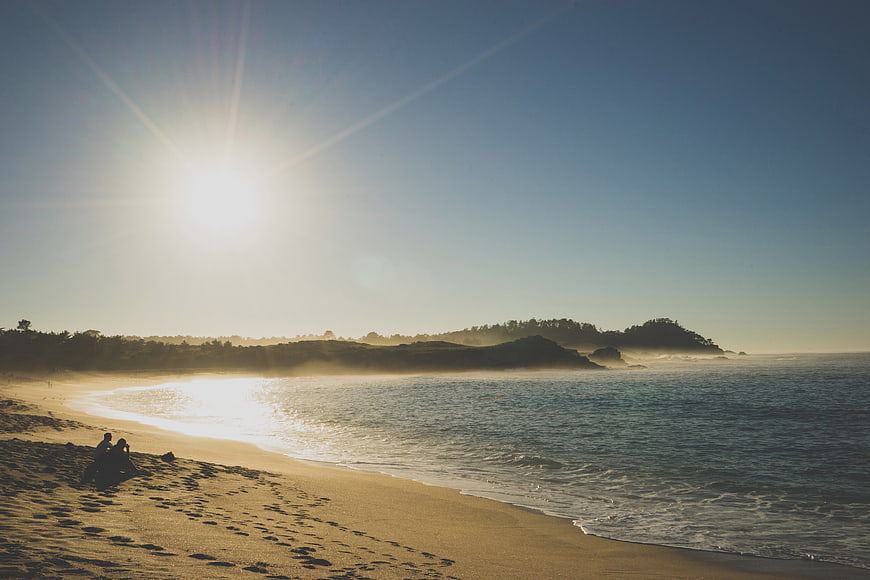 Couple Sitting on Sandy Beach at Golden Hour