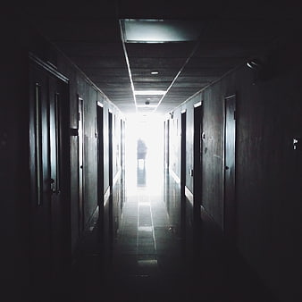 Silhouette of person walking down dark hospital corridor