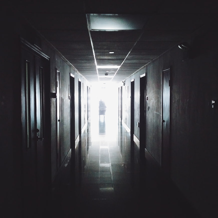 Silhouette of person walking down dark hospital corridor