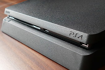 Close-up of black PlayStation 4 console front panel on wooden table