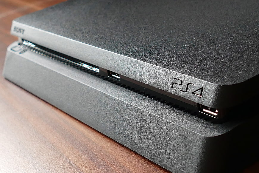 Close-up of black PlayStation 4 console front panel on wooden table