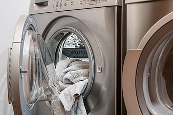 Open washing machine with gray towels inside drum