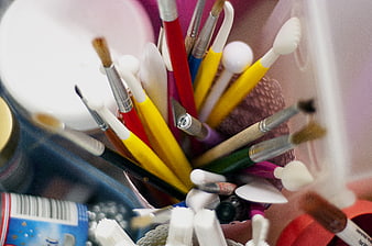Close-up of colorful art brushes and craft supplies in a container