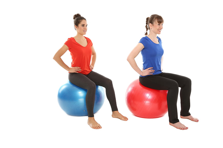 Two women sitting on exercise balls in gym wear