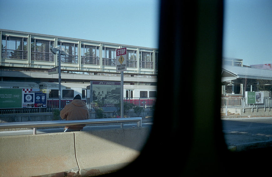 Commuter waiting at JFK UMass train station viewed through window