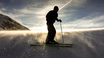 Silhouette of skier carving through powder snow in mountains
