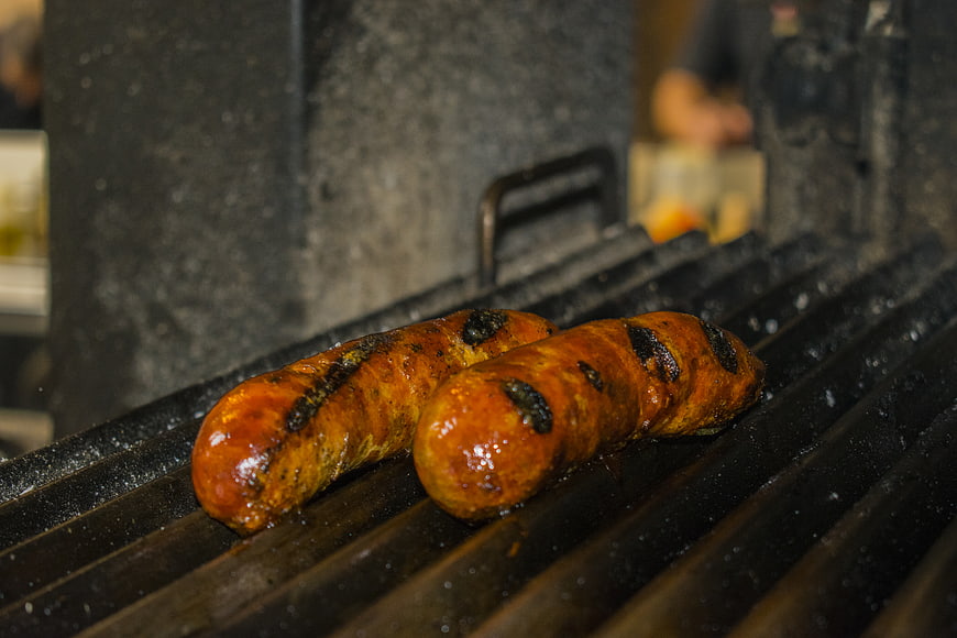 Grilled sausages cooking on a barbecue grill grate