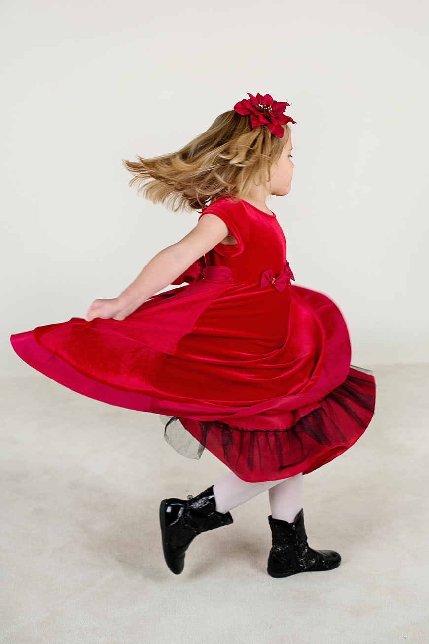 Little girl in red dress spinning with joyful motion